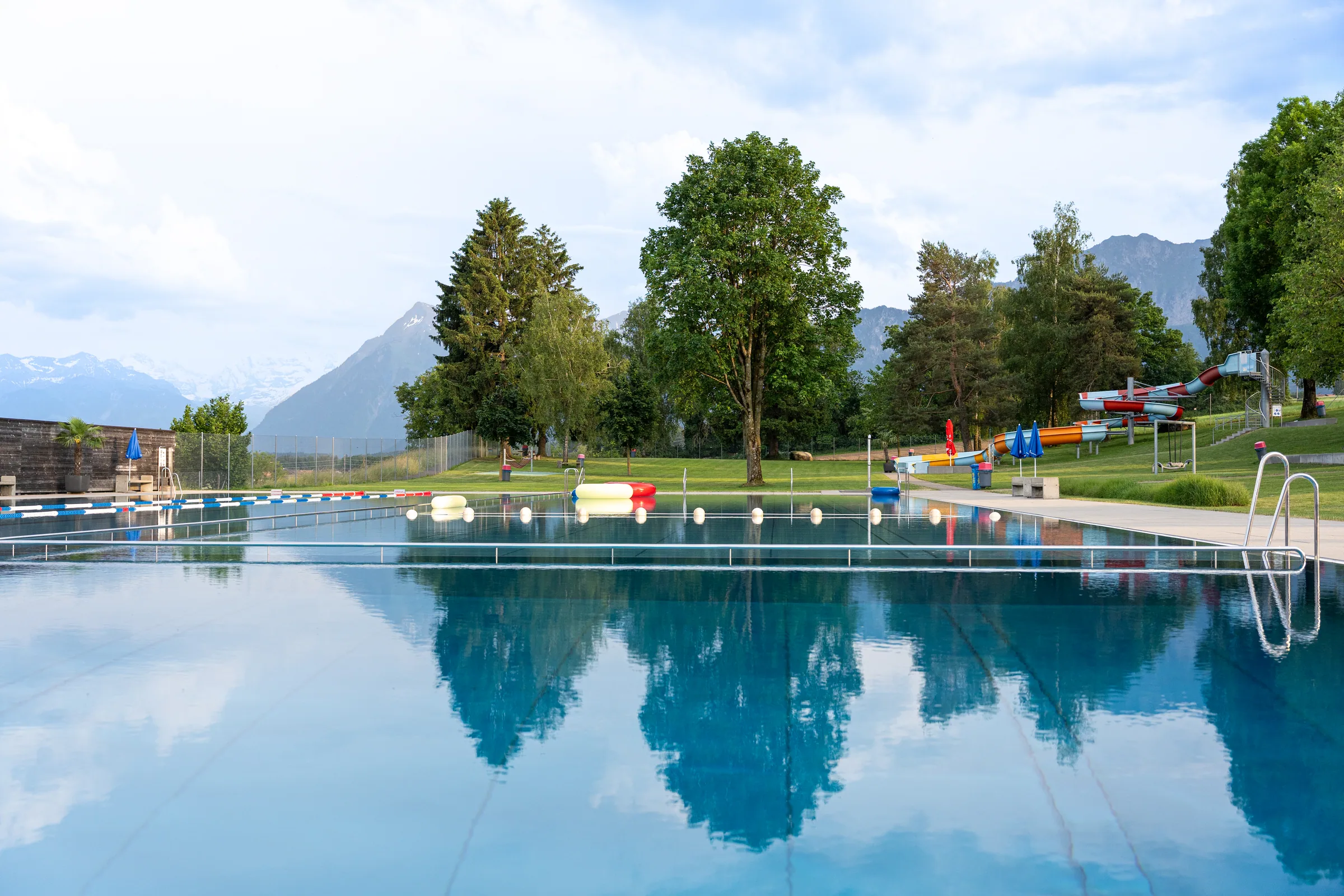 Ruhiges Schwimmbecken der Badi Uetendorf mit Bergblick und Spiegelung